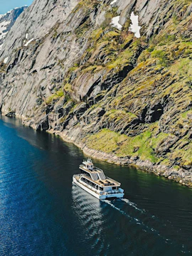 Cruise ship navigating Trollfjord's narrow waters, Lofoten, with steep rocky cliffs.