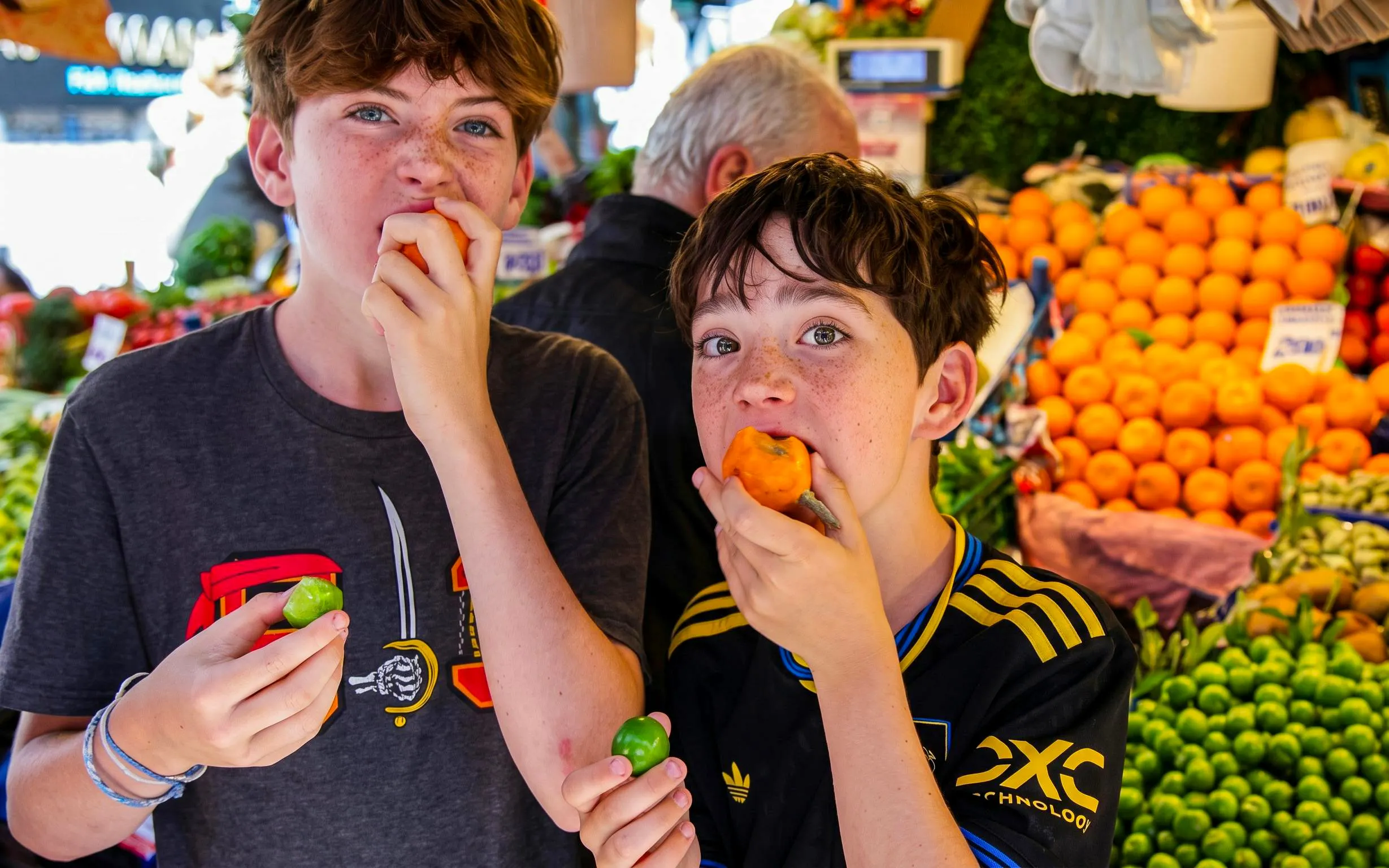 Boys tasting fresh produce at an Istanbul market during a food tour.