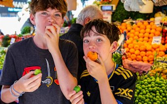 Boys tasting fresh produce at an Istanbul market during a food tour.