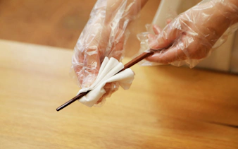 Hands polishing chopsticks with cloth at Ginza workshop.
