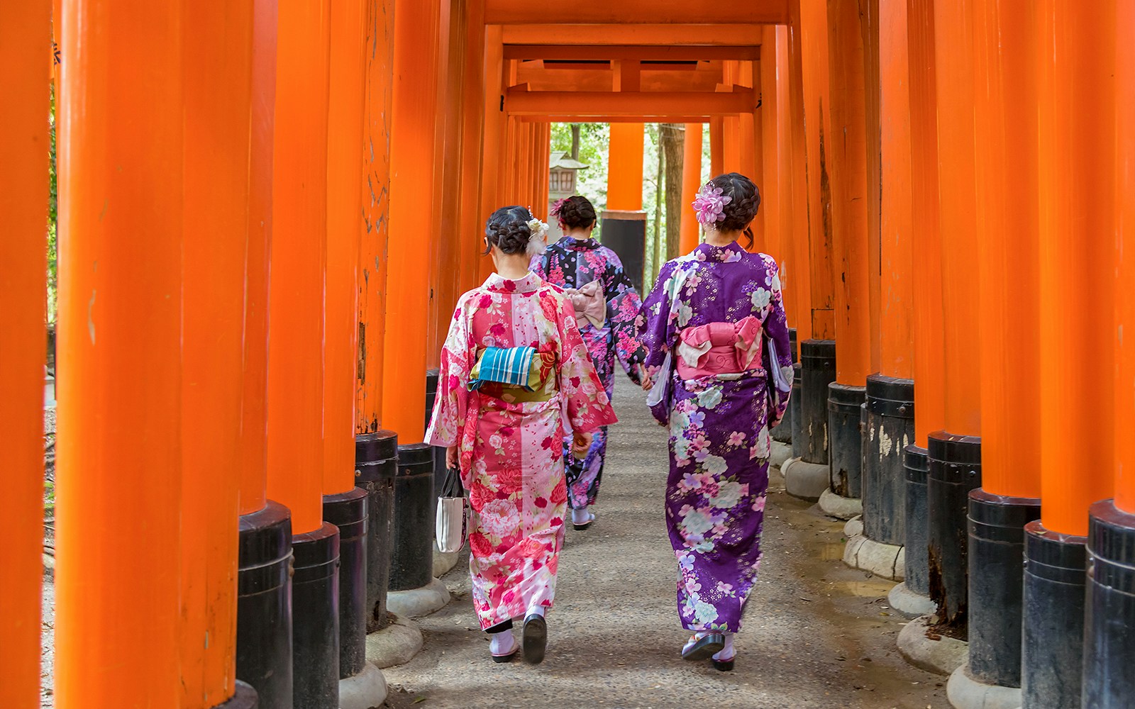 Visitors in kimonos walking through torii gates at Fushimi Inari Taisha, Kyoto.