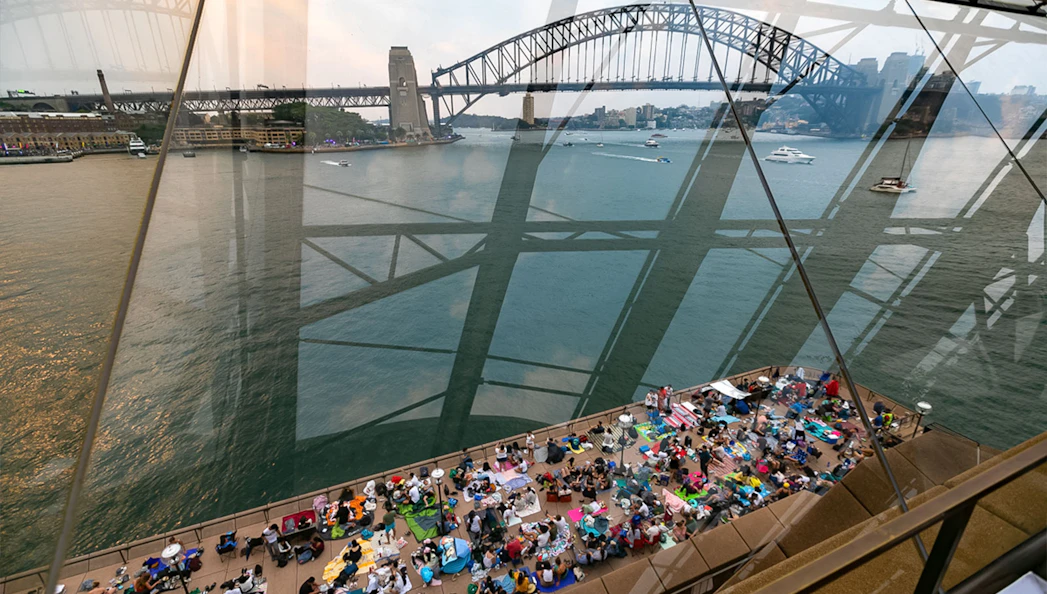 Sydney Opera House view with people gathered for NYE Opera Gala, overlooking Sydney Harbour Bridge.