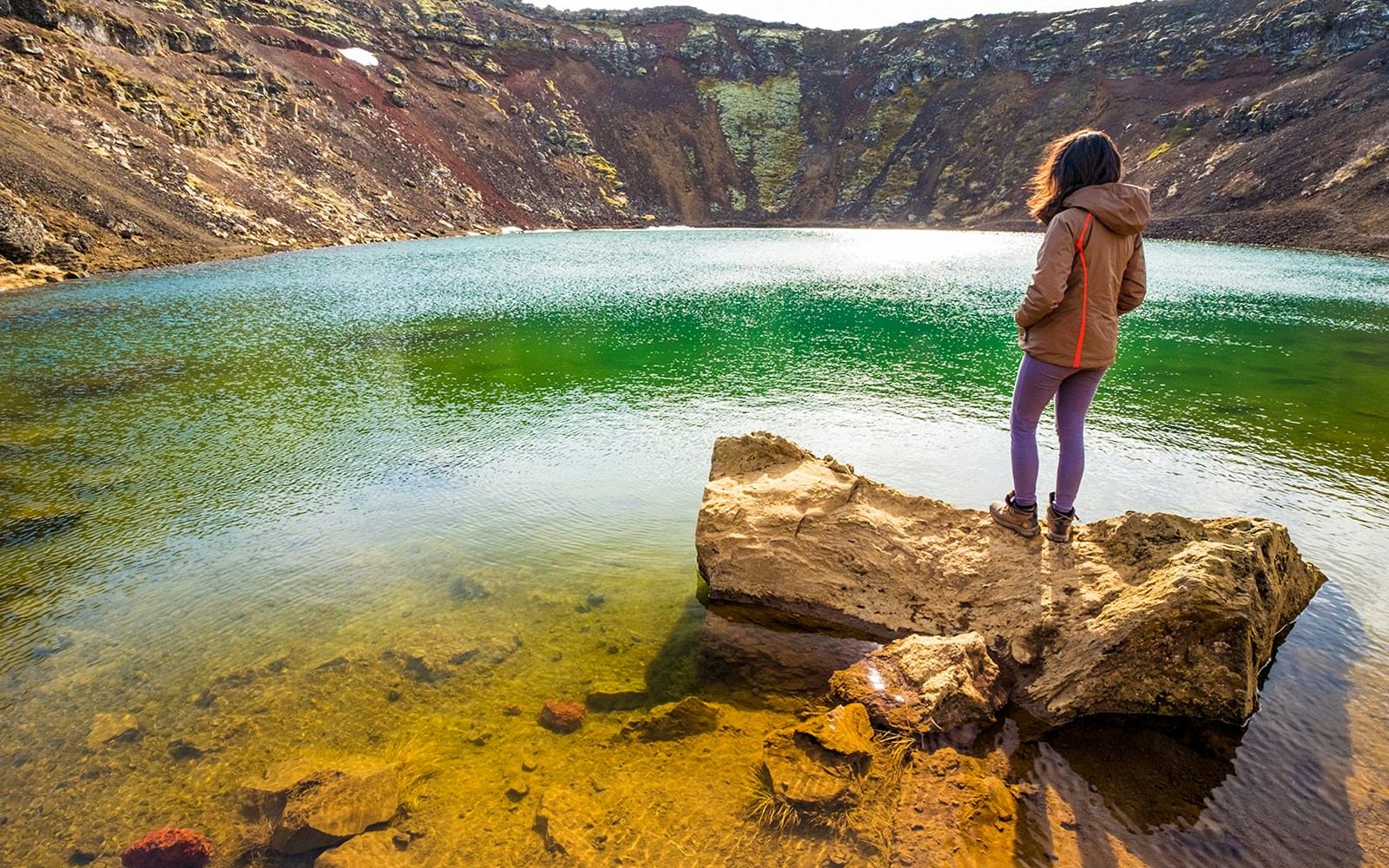 Kerid Crater Lake in Iceland with vibrant blue water surrounded by red volcanic rock.
