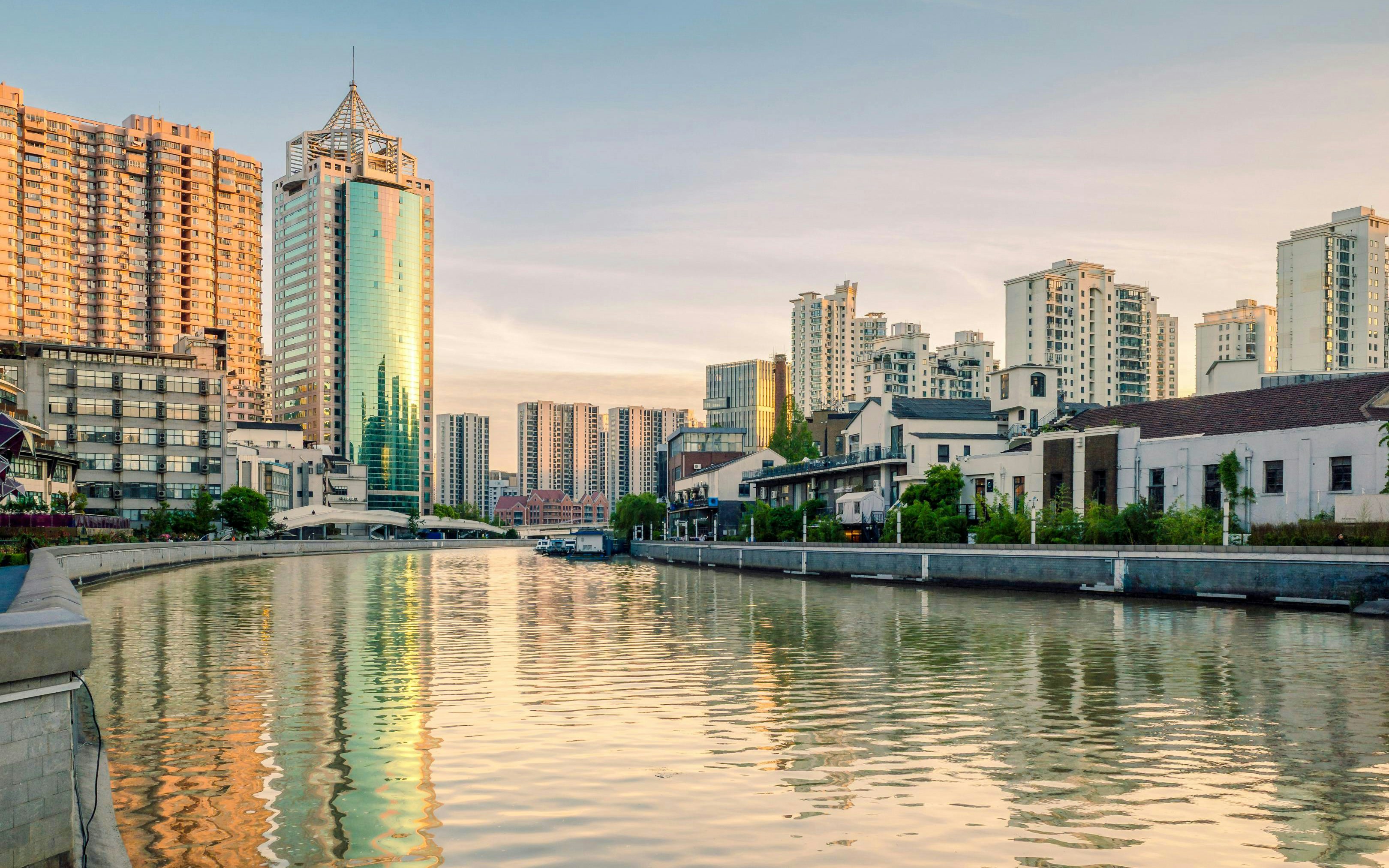 Golden sunset reflections on Suzhou Creek with modern residential buildings in Shanghai, China.