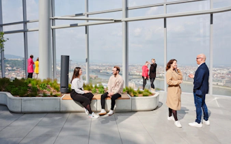 People enjoying the view from SkyDeck at MOL Campus, Budapest, overlooking the city and river.