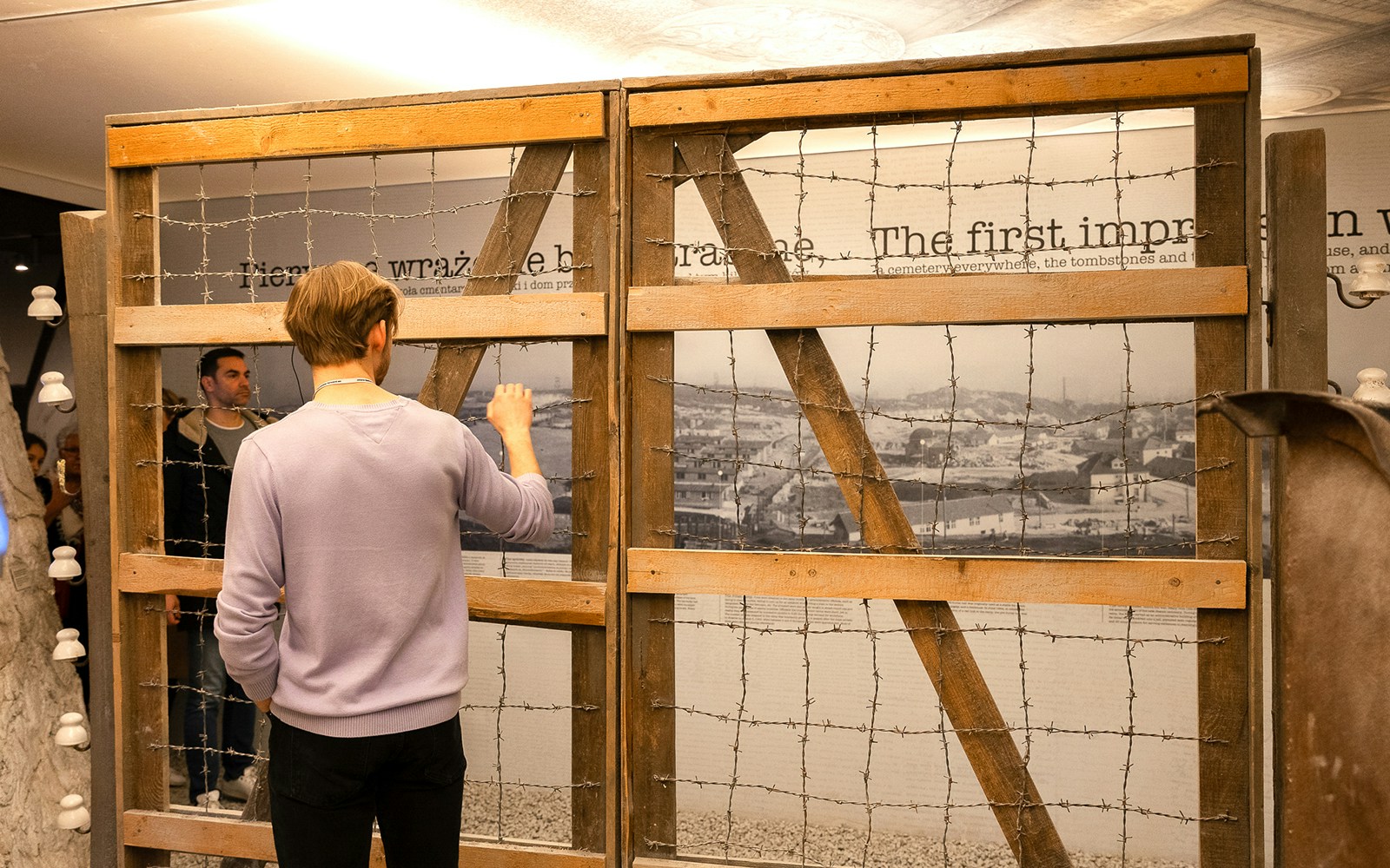 Visitor examines barbed wire exhibit at Dachau concentration camp display in Oskar Schindler's Factory.