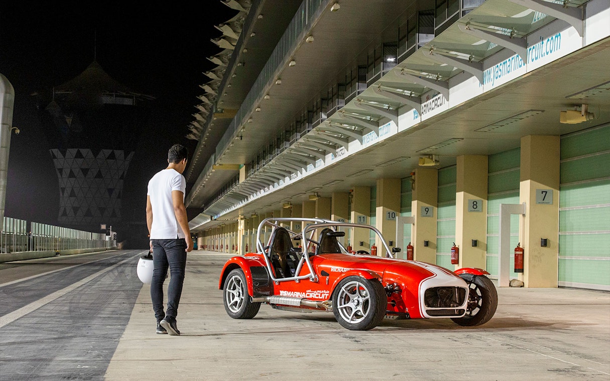 Caterham Seven 360 parked at Yas Marina Circuit with a person holding a helmet nearby.