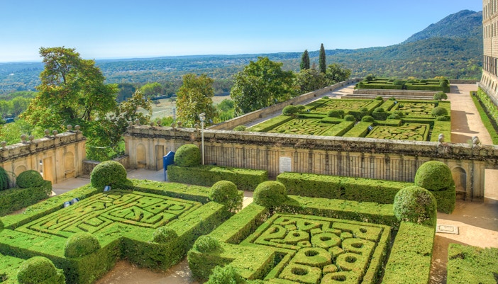 Gardens of the Royal Seat of San Lorenzo de El Escorial with manicured hedges near Madrid, Spain.