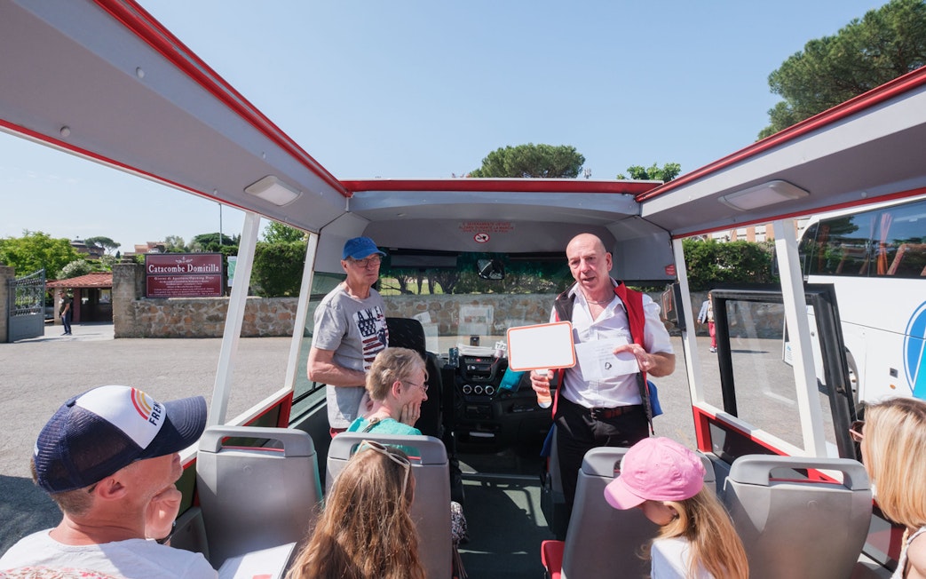 Tour guide speaking to visitors on a bus at Catacombs of Domitilla, Rome.