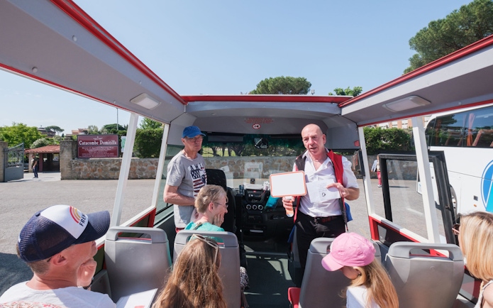 Tour guide speaking to visitors on a bus at Catacombs of Domitilla, Rome.