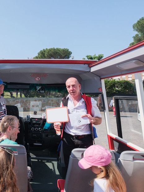 Tour guide speaking to visitors on a bus at Catacombs of Domitilla, Rome.