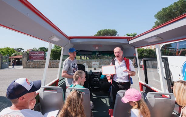 Tour guide speaking to visitors on a bus at Catacombs of Domitilla, Rome.