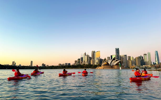 Kayakers on Sydney Harbour with Opera House and skyline in view.