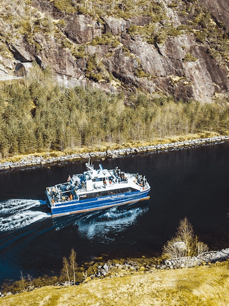 Mostraumen Fjord Cruise boat sailing through narrow fjord with rocky cliffs and trees in Norway.