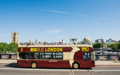 Big Bus tour in London with passengers, passing by the Houses of Parliament.