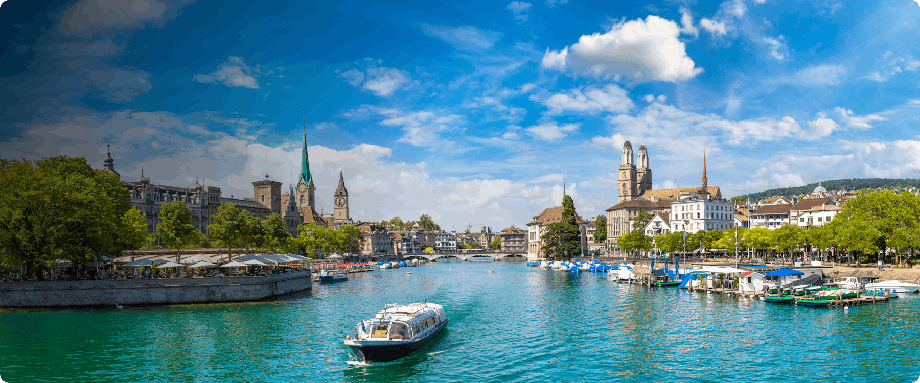 Boat on Limmat River with view of Zurich's historic buildings and Grossmünster church.