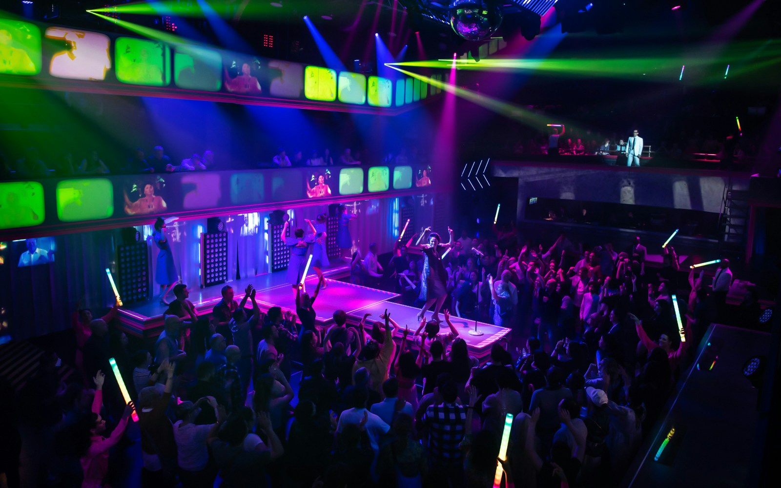 Crowd enjoying vibrant nightclub performance at Here Lies Love event.