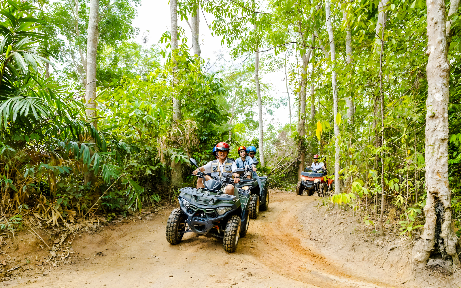 People riding quad bikes through a lush forest trail at Flying Hanuman.