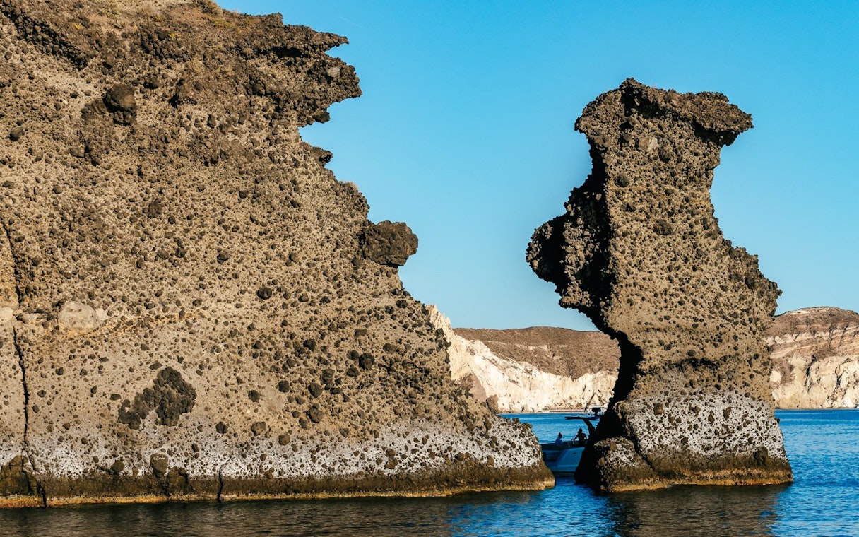 Indian Rocks formations along Santorini's southern coast with a boat in the sea.