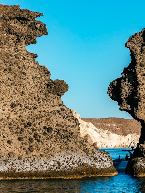 Indian Rocks formations along Santorini's southern coast with a boat in the sea.