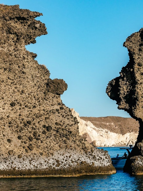Indian Rocks formations along Santorini's southern coast with a boat in the sea.