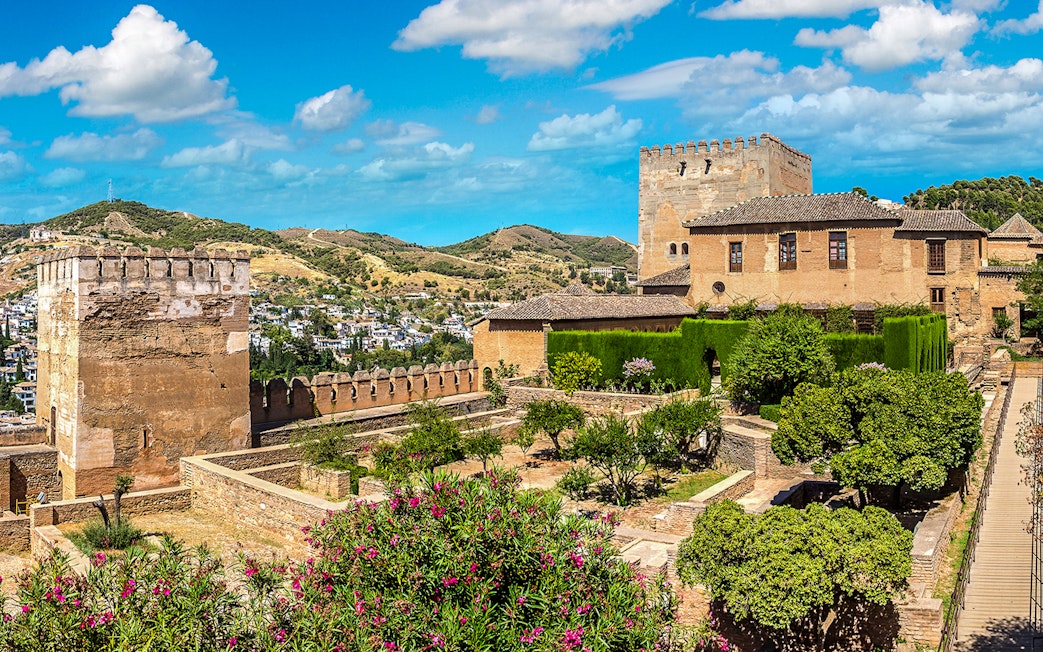 Alhambra fortress gardens and towers in Granada, Spain, with scenic hillside view.