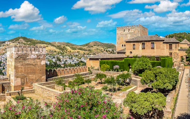 Alhambra fortress gardens and towers in Granada, Spain, with scenic hillside view.