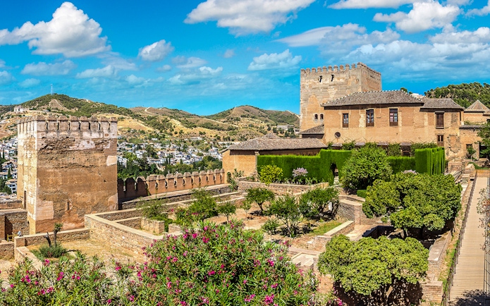 Alhambra fortress gardens and towers in Granada, Spain, with scenic hillside view.