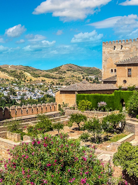 Alhambra fortress gardens and towers in Granada, Spain, with scenic hillside view.
