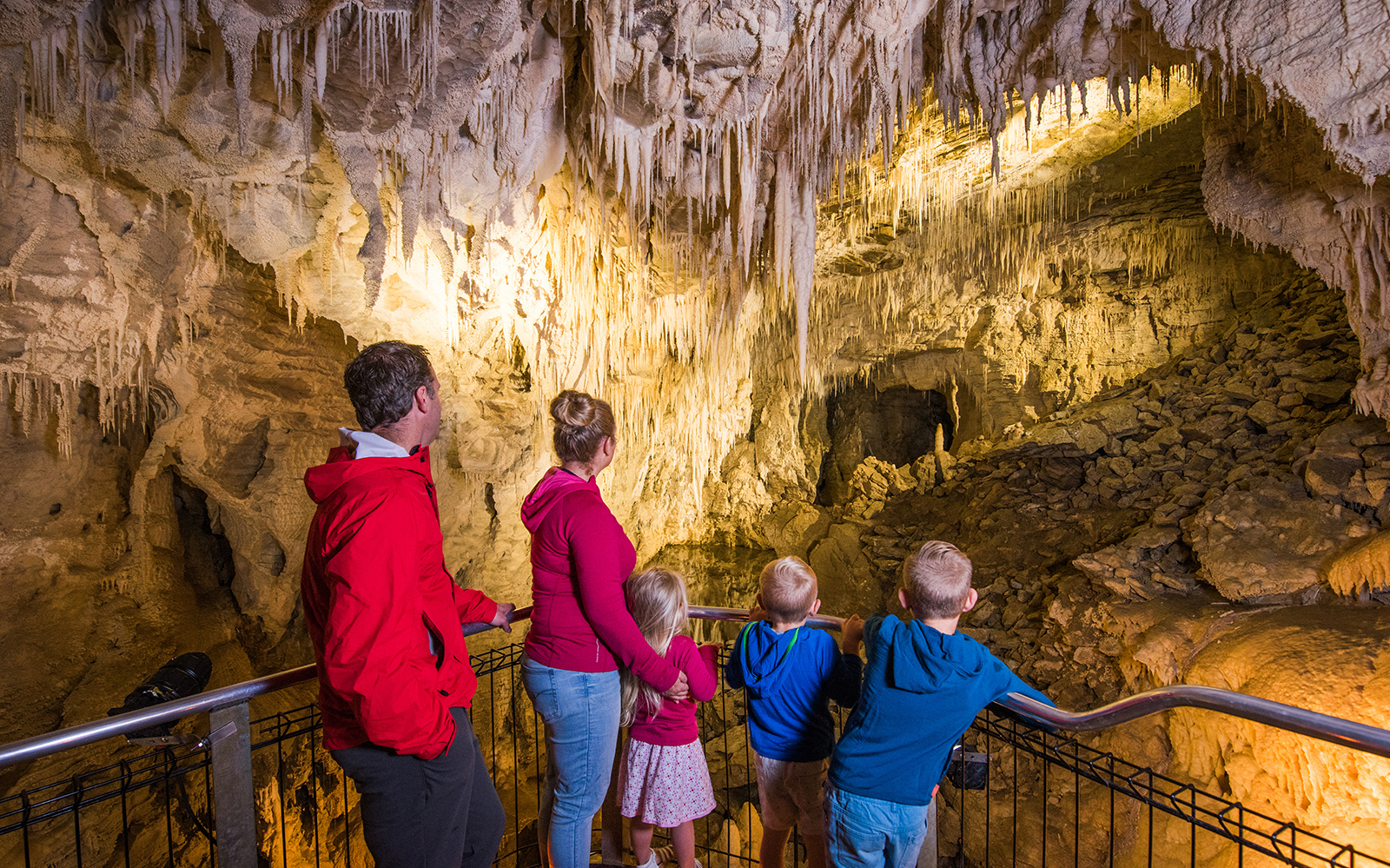 Visitors exploring the illuminated stalactites and stalagmites inside Aranui Cave, New Zealand.