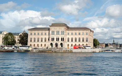 National Museum in Stockholm viewed from across the water with tour buses in front.