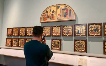 Visitor using audio guide at Academia Gallery, viewing religious paintings, Florence.