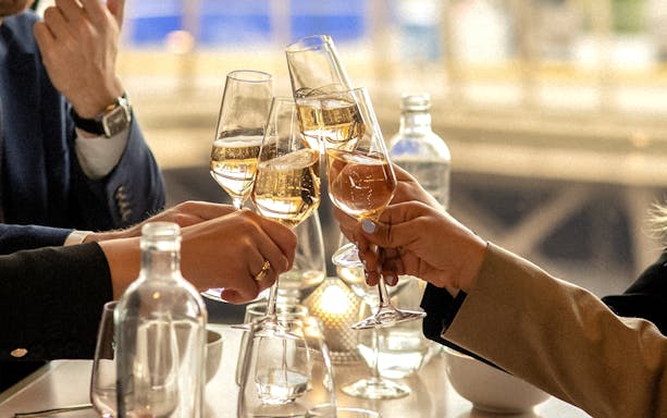 Toasting with champagne glasses during Christmas dinner on the Eiffel Tower's first floor in Paris.