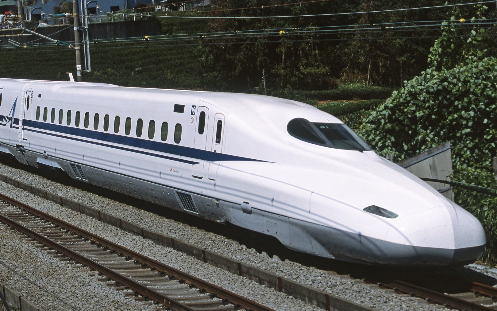 Tokaido Shinkansen train traveling on tracks in Japan.