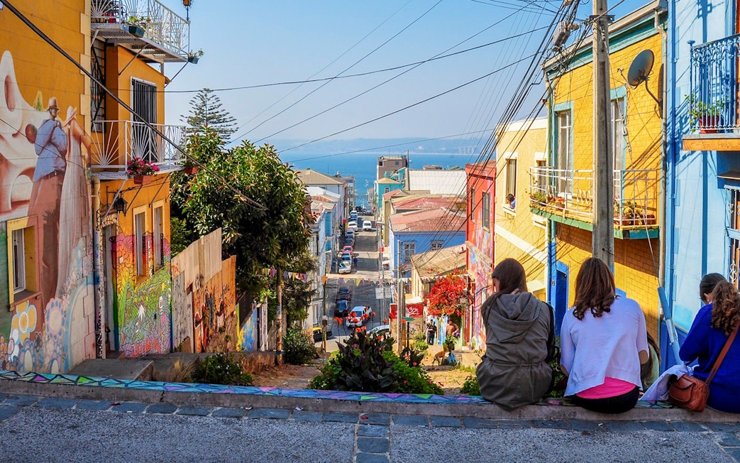 Tourists sitting on a colorful street enjoying the view of Valparaíso, Chile.