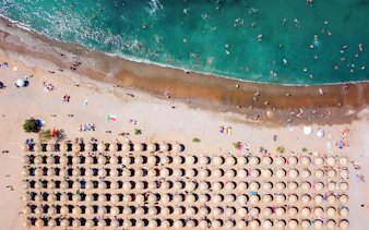 Aerial view of Agios Nikolaos beach with sun umbrellas and swimmers, Anavysos, Athens Riviera, Greece.