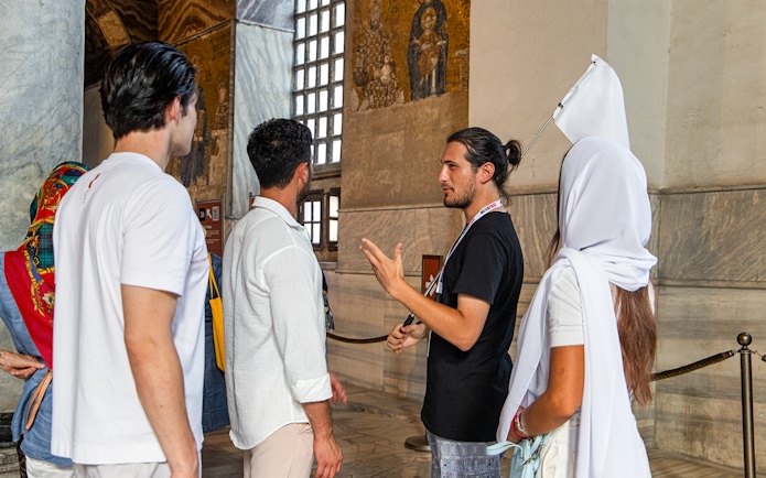 Tour guide explaining mosaics to visitors inside Hagia Sophia, Istanbul.