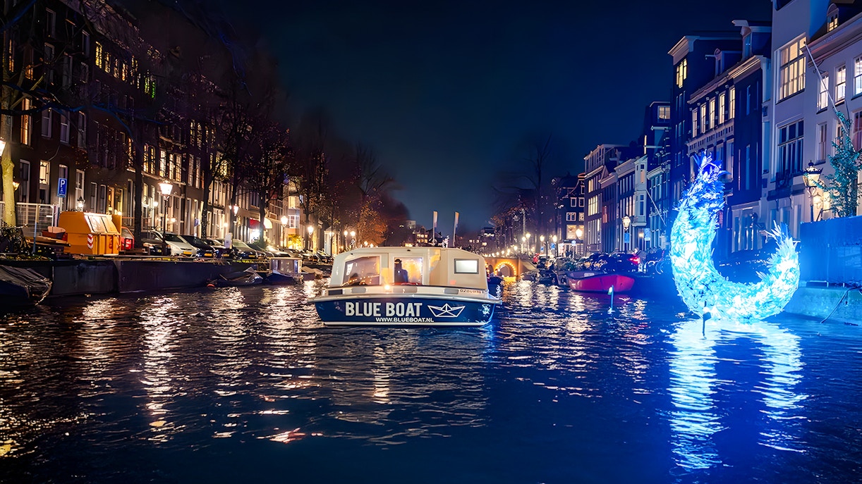 Amsterdam canal with illuminated art installation during Light Festival evening cruise.