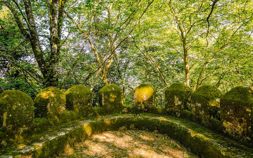 Moss-covered stone walls of Moorish Castle's second ring in Sintra, Portugal, surrounded by trees.