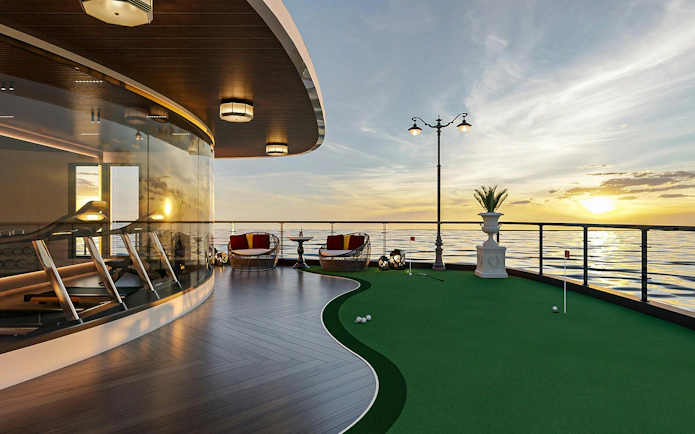 Luxury cruise deck with mini-golf and seating area at sunset, Lan Ha Bay.