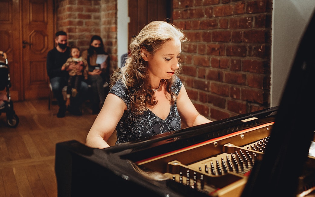 Pianist performing Chopin at Old Town recital with audience in background.