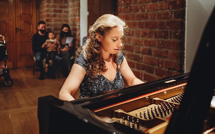 Pianist performing Chopin at Old Town recital with audience in background.