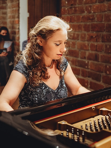 Pianist performing Chopin at Old Town recital with audience in background.