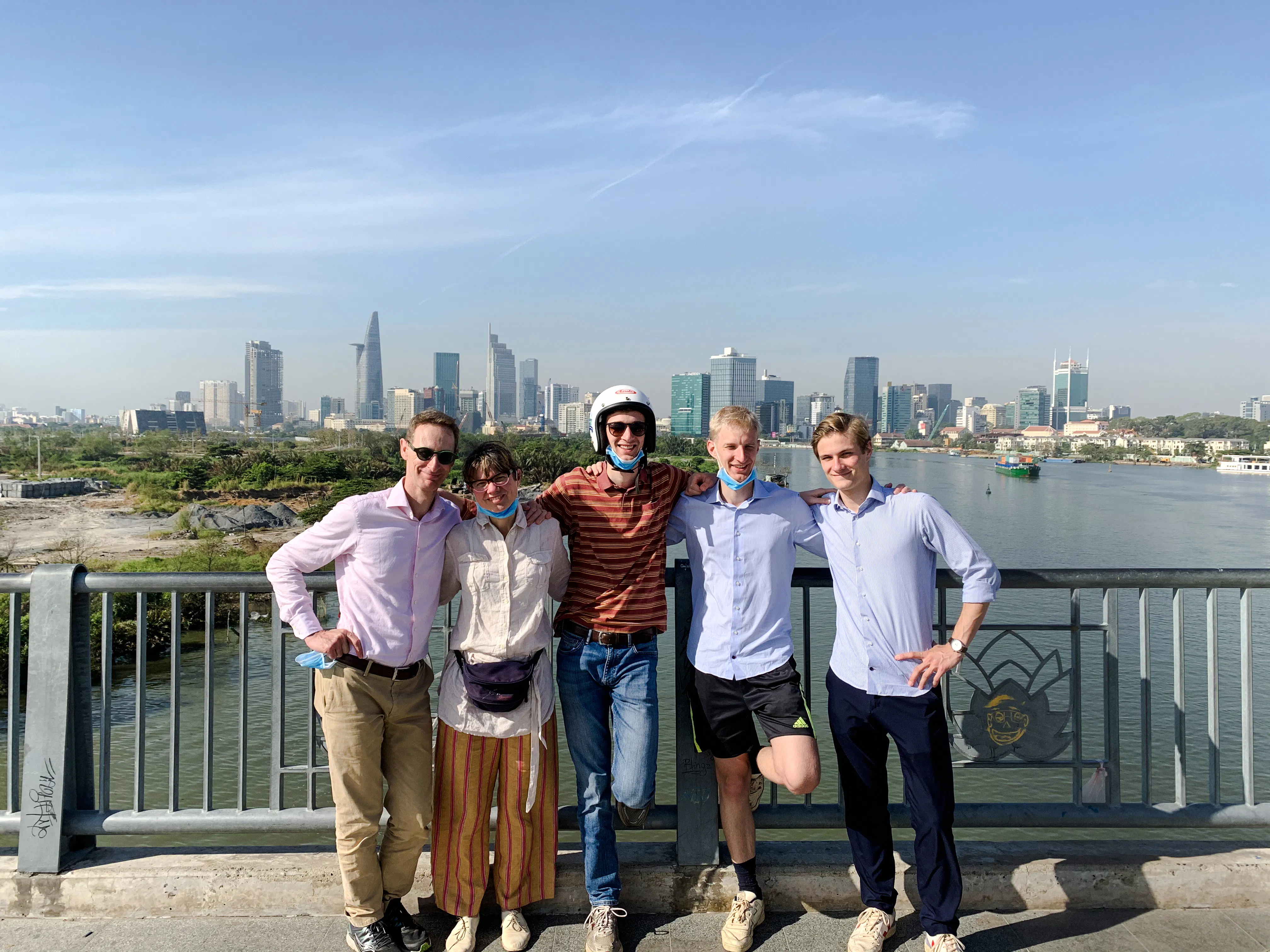Group of tourists on a bridge with Ho Chi Minh City skyline during Saigon Hidden Gems Day Tour by Scooter.