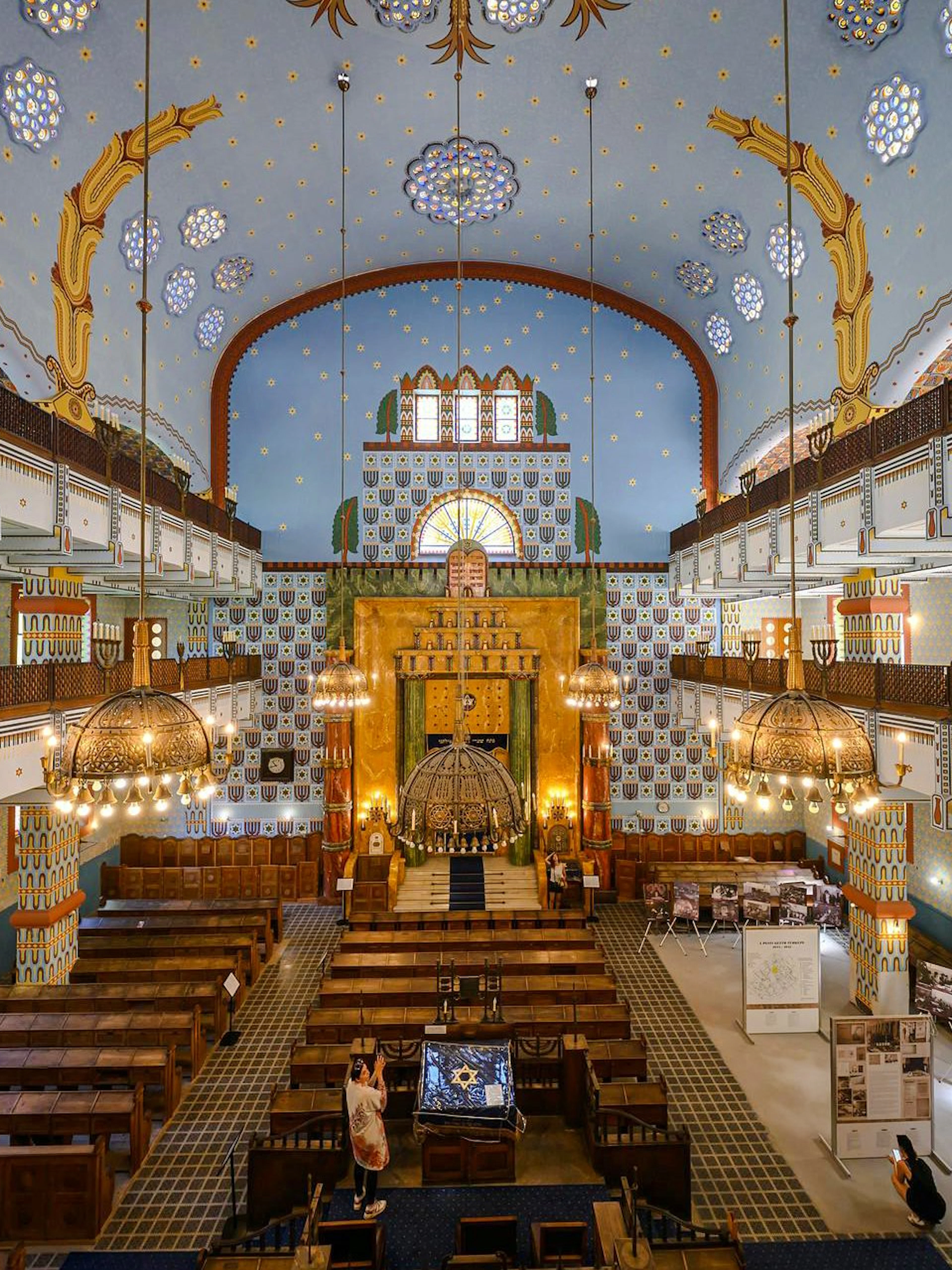 Interior of Kazinczy Synagogue in Budapest with ornate ceiling and wooden pews.