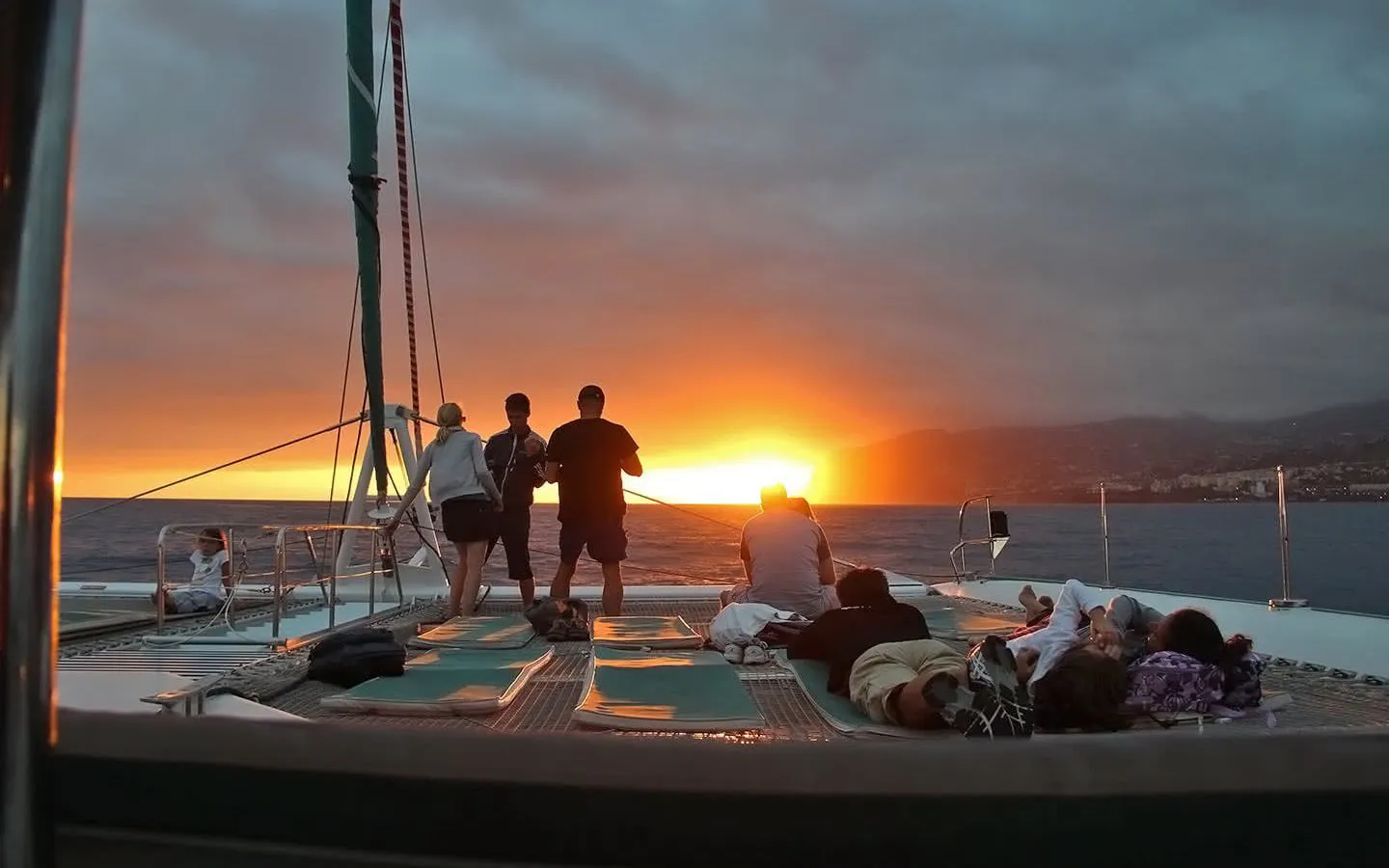 Catamaran passengers watching sunset on Madeira dolphin and whale tour.