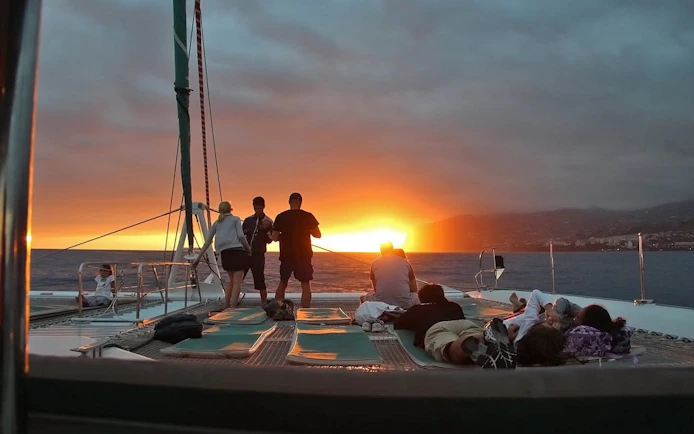Catamaran passengers watching sunset on Madeira dolphin and whale tour.