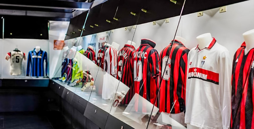 San Siro stadium dressing room with football jerseys on display.