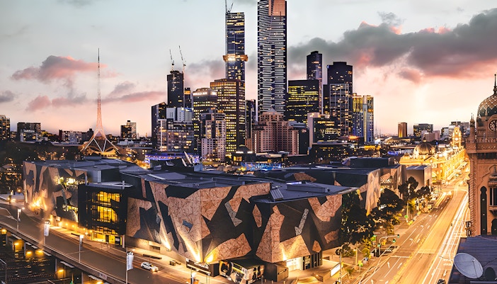 Ian Potter Center at NGV Australia with Melbourne skyline at dusk.