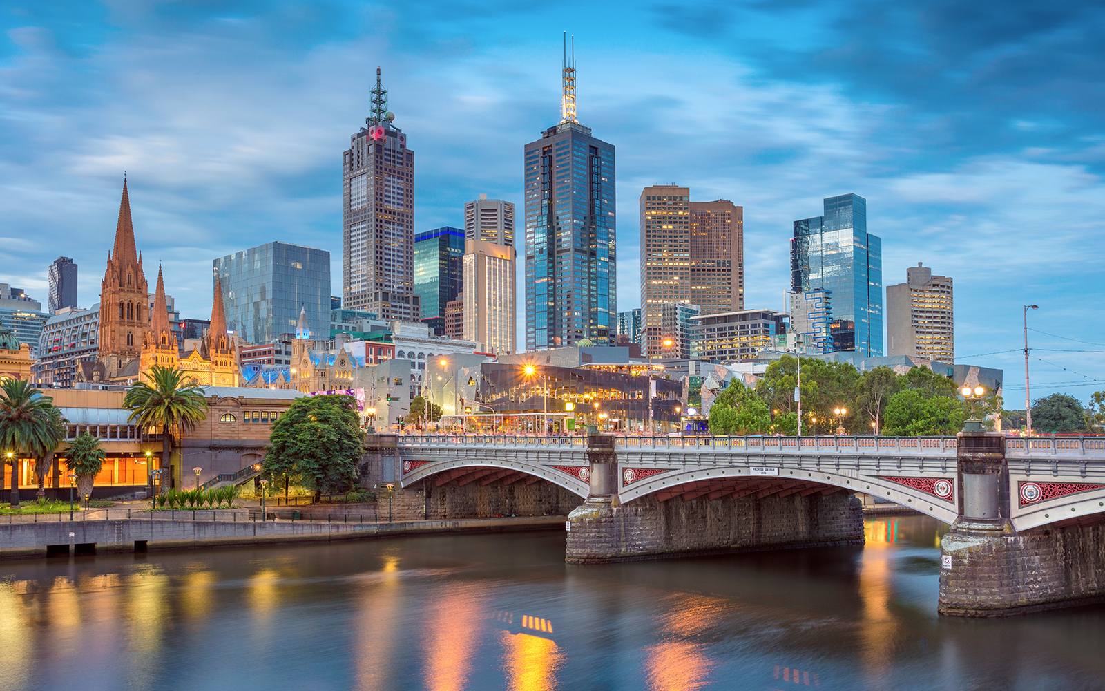 Melbourne city skyline with Yarra River and bridge at dusk.